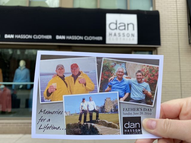 A printed photo of Dan Hasson and his family is held up in front of his storefront