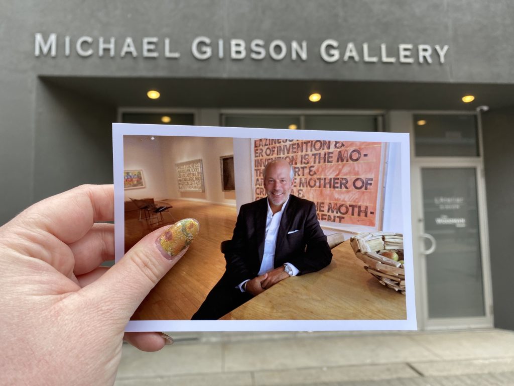 A printed photograph of owner Michael Gibson held up in front of the local Michael Gibson Gallery.