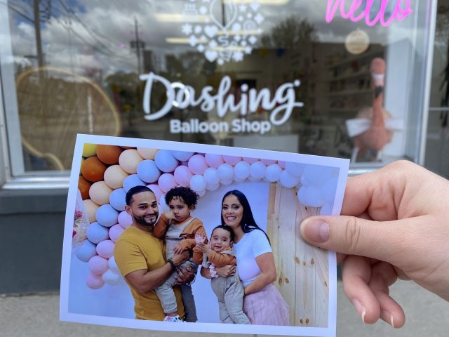 A printed photo of Joyce and Julius Hinetroza held up in front of their store front in Downtown London.