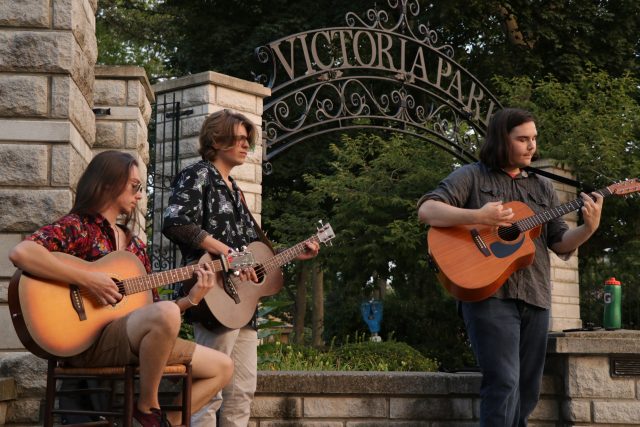 Three musicians playing guitar at Victoria Park.